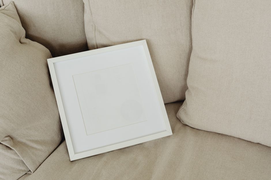 Simple and cozy living room setup featuring a blank wooden frame on a beige sofa.