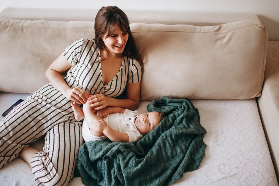 A mother and her baby enjoying a relaxed moment on the sofa at home.